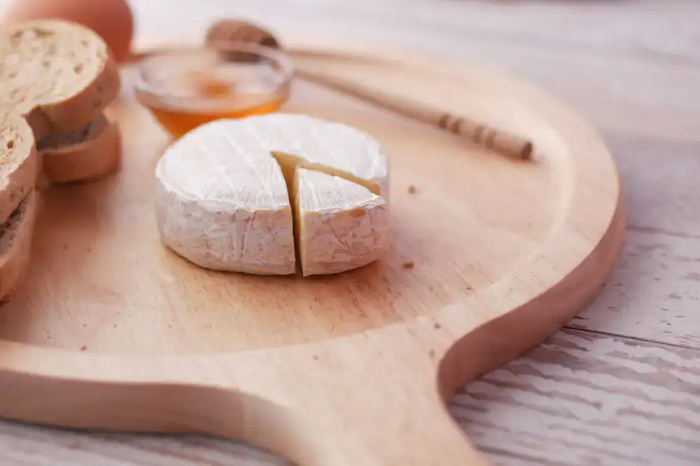 A wooden board featuring only varied artisan cheeses and honey