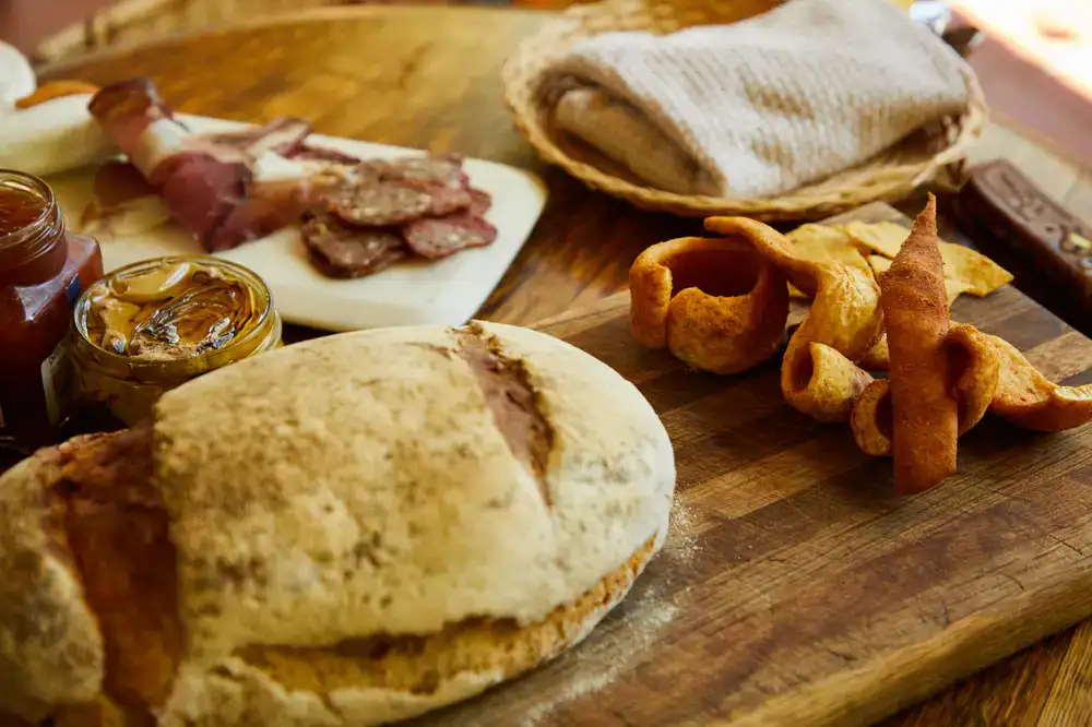 A woven hamper filled with wrapped deli goods and preserves