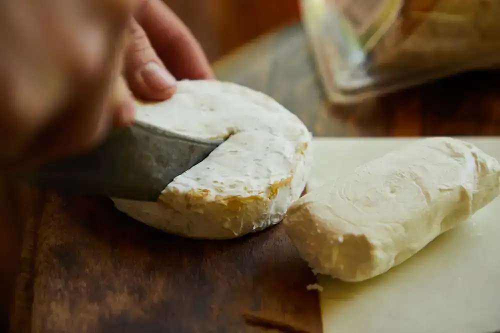 A wheel of aged farmhouse cheese being cut